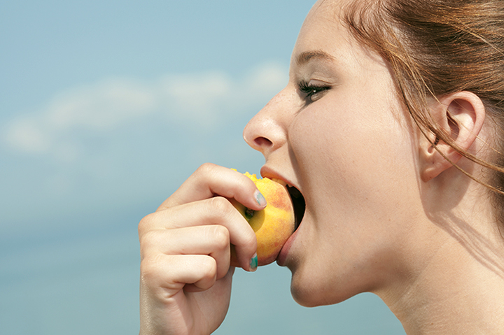 Девушка кушает персик