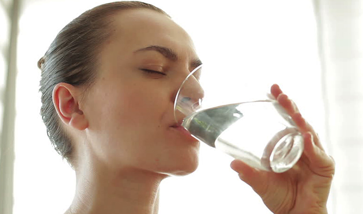 Женщина пьет щелочную воду