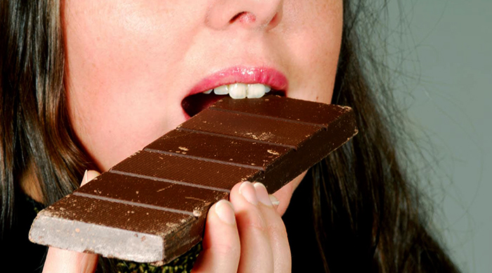 Женщина кушает шоколад